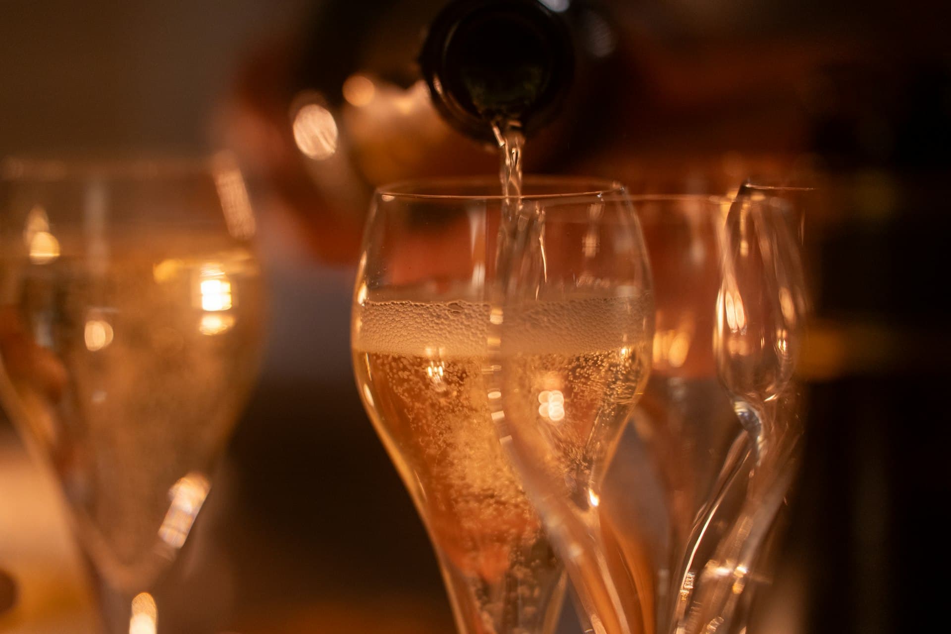 Champagne hälls upp i mousserande glas med varm bakgrundsbelysning.